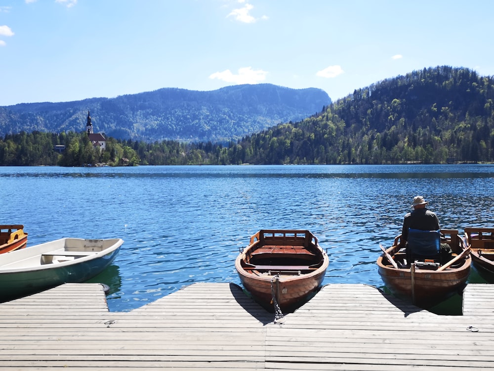 man and woman sitting on brown wooden boat on lake during daytime