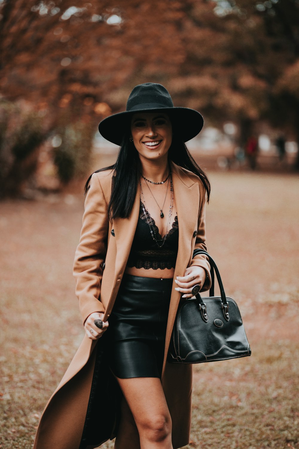 Femme en blazer marron et jupe noire portant un chapeau noir