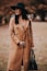 woman in brown coat standing on brown field during daytime