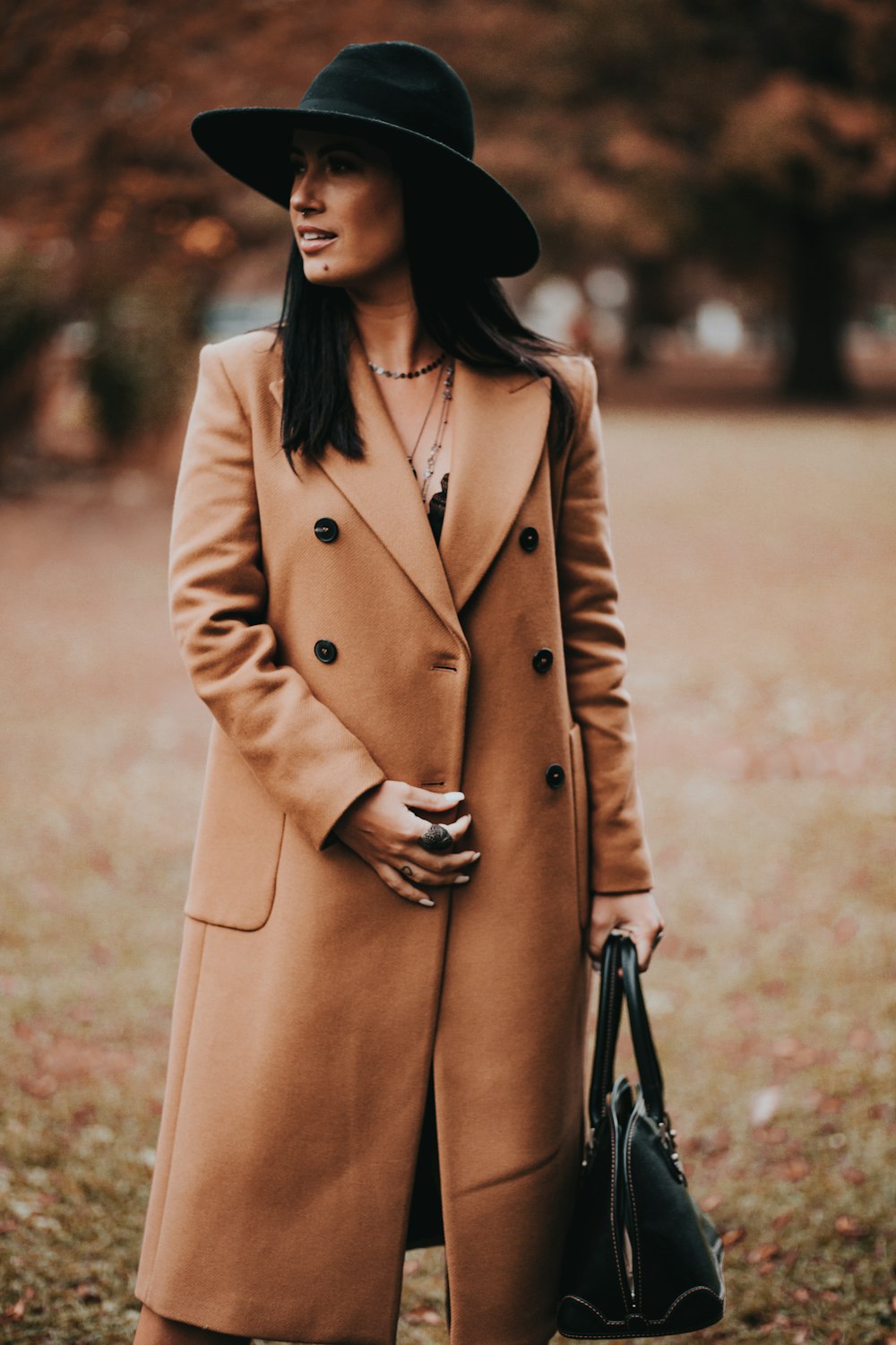 낮 동안 갈색 들판에 서 있는 갈색 코트를 입은 여자