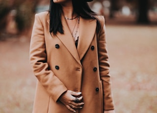 woman in brown coat standing on brown field during daytime