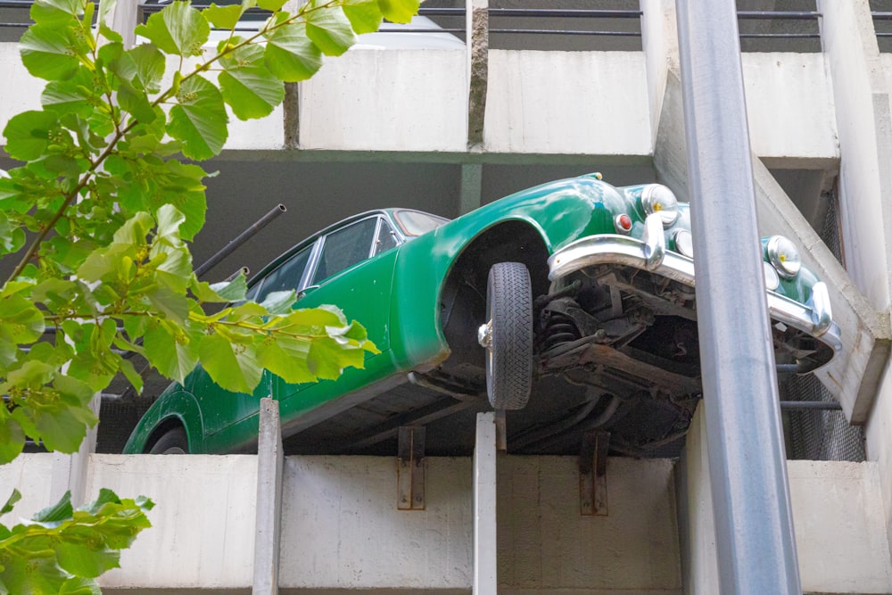 green car parked beside white wall