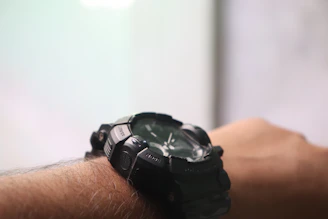 Close-up of a trendy black and red men's watch on a wrist with streetwear background.