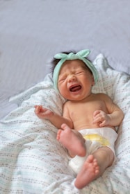 a baby crying while laying on a bed