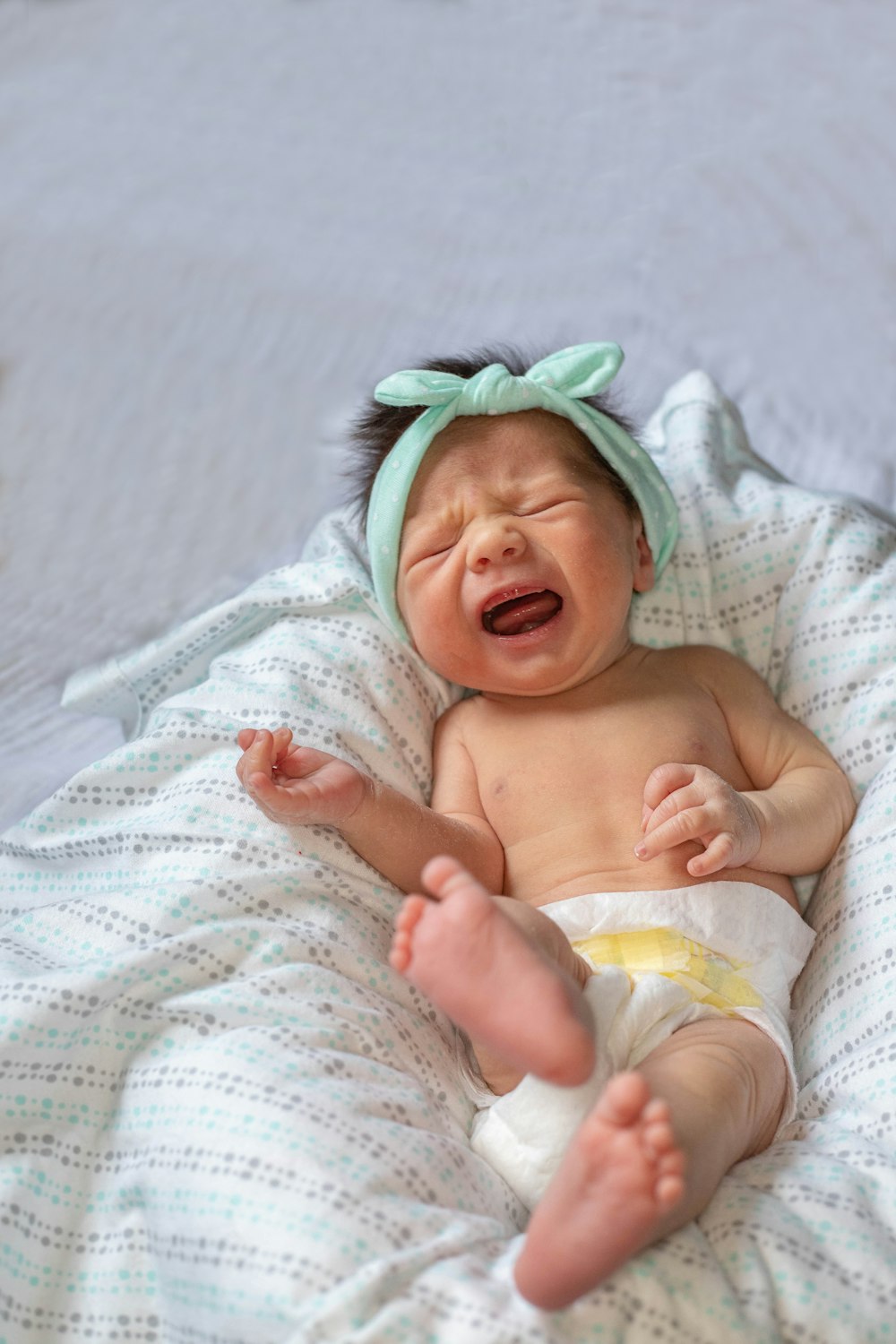 un bambino che piange mentre è sdraiato su un letto