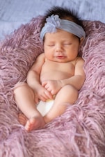 baby lying on pink textile