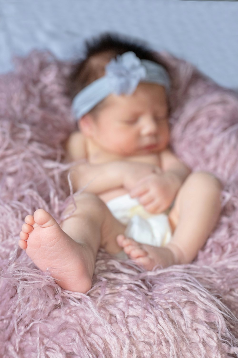 baby in white diaper lying on grey textile