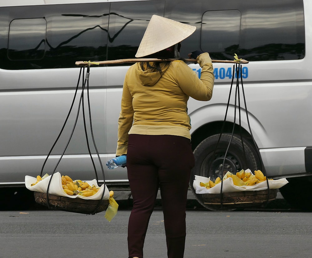 Femme en chemise à manches longues jaune et jean en denim bleu tenant un sac en papier blanc