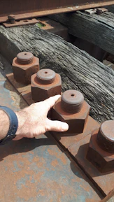 Hands gripping a steel wrench tightening bolts on a heavy-duty construction frame.