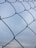 A close-up of galvanized farm fencing with sturdy concrete bases under a bright sky.