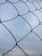 A close-up of galvanized farm fencing with sturdy concrete bases under a bright sky.