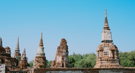 brown concrete building near green trees during daytime in Ayutthaya Historical Park Thailand