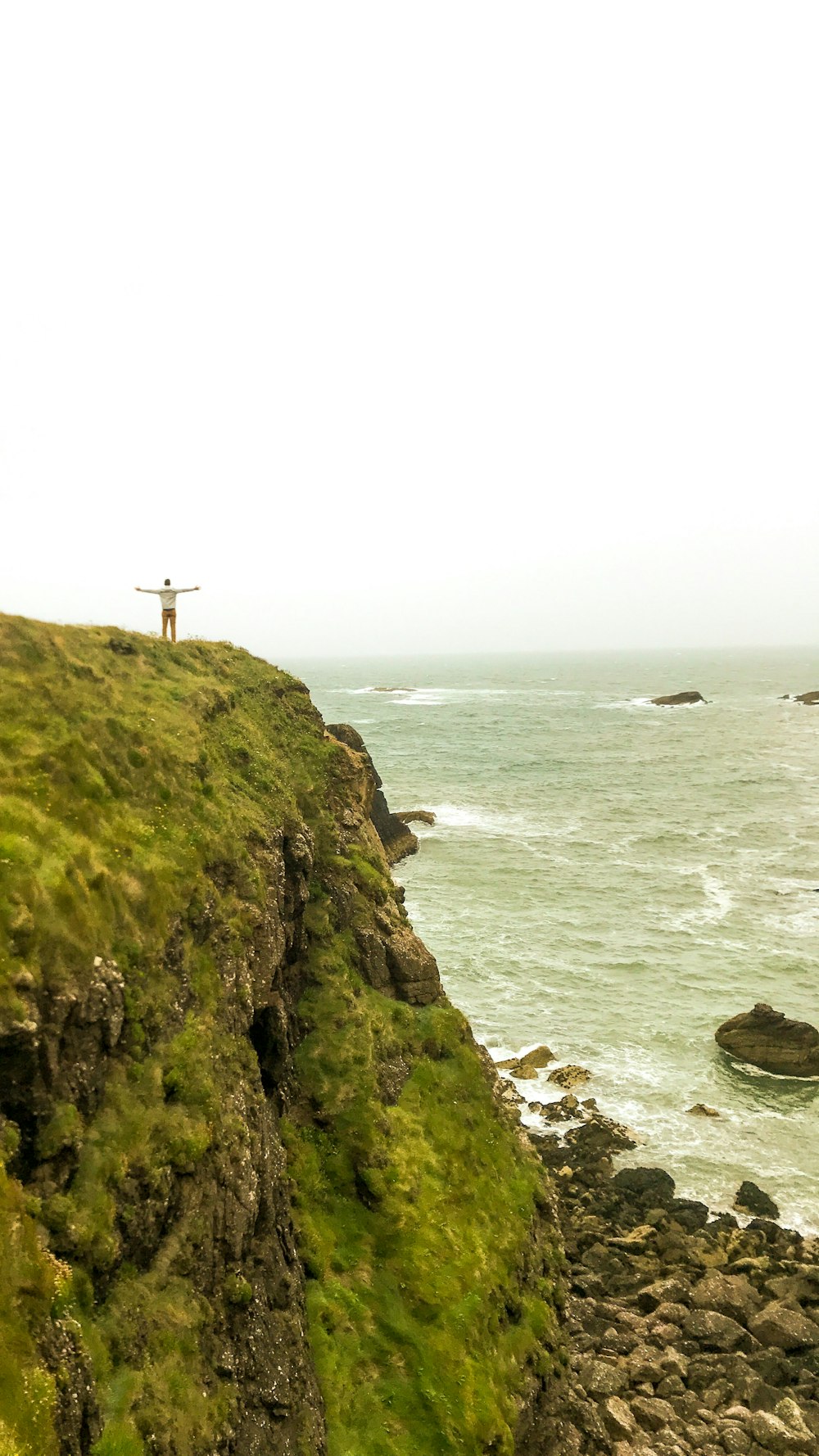 white cross on green mountain near body of water during daytime