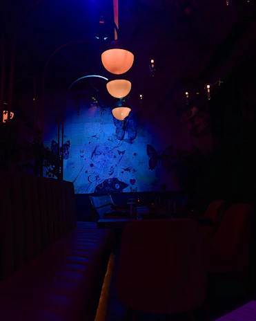 A dimly lit room with soft violet light casting shadows on minimalist decor, evoking mystery and calm.