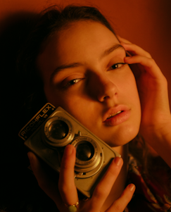 A candid portrait of a photographer holding a vintage camera, surrounded by natural light.