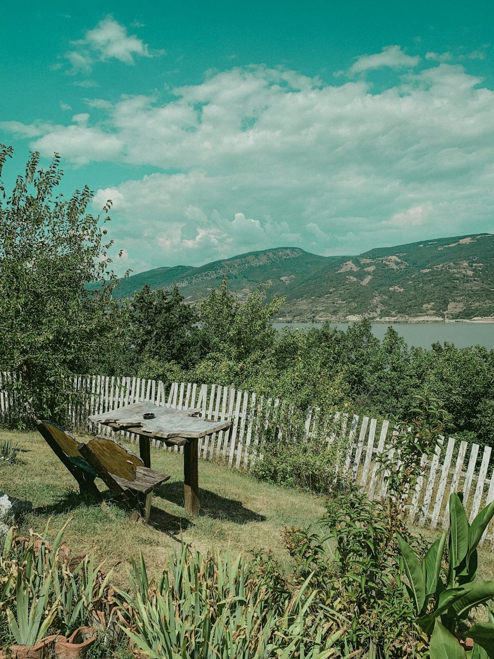 brown wooden picnic table near white wooden fence and green grass field during daytime