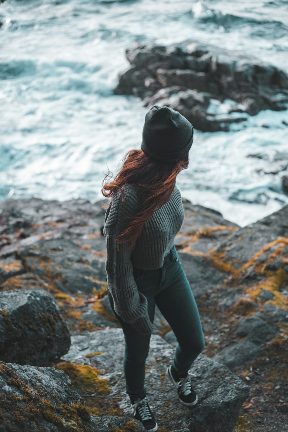 woman in black and white striped long sleeve shirt and blue denim jeans standing on rocky