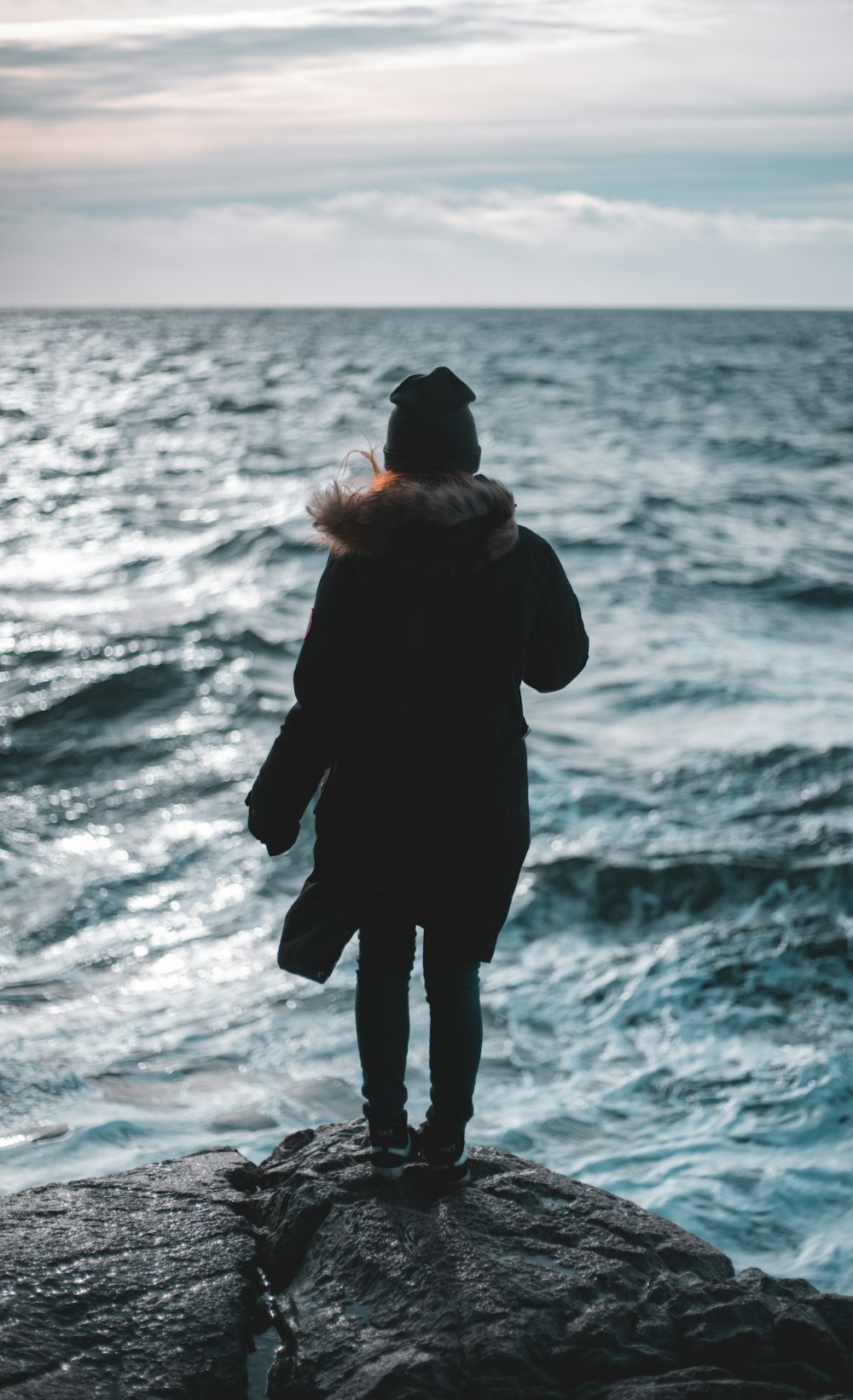 man in black jacket standing on seashore during daytime