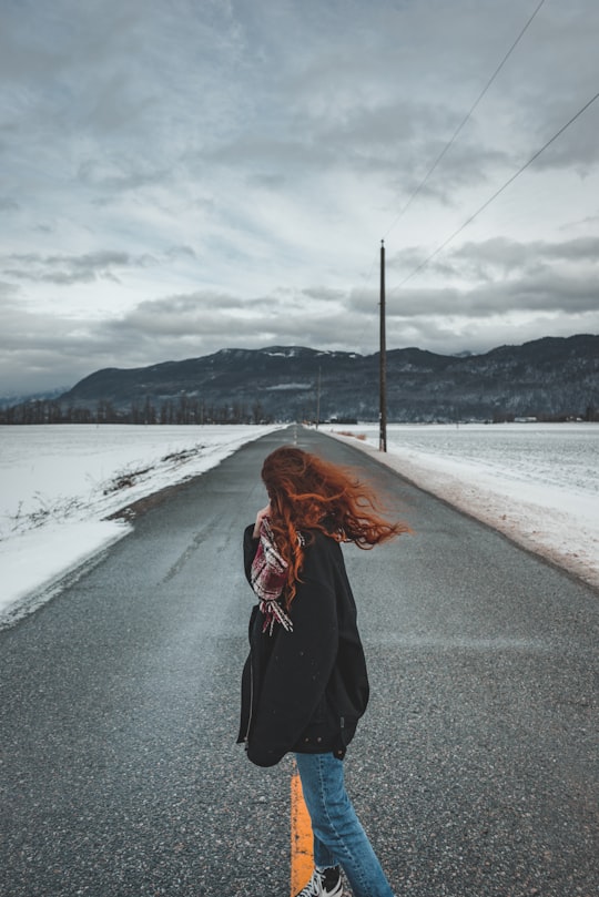 woman in black jacket standing on gray concrete road during daytime in Hope Canada