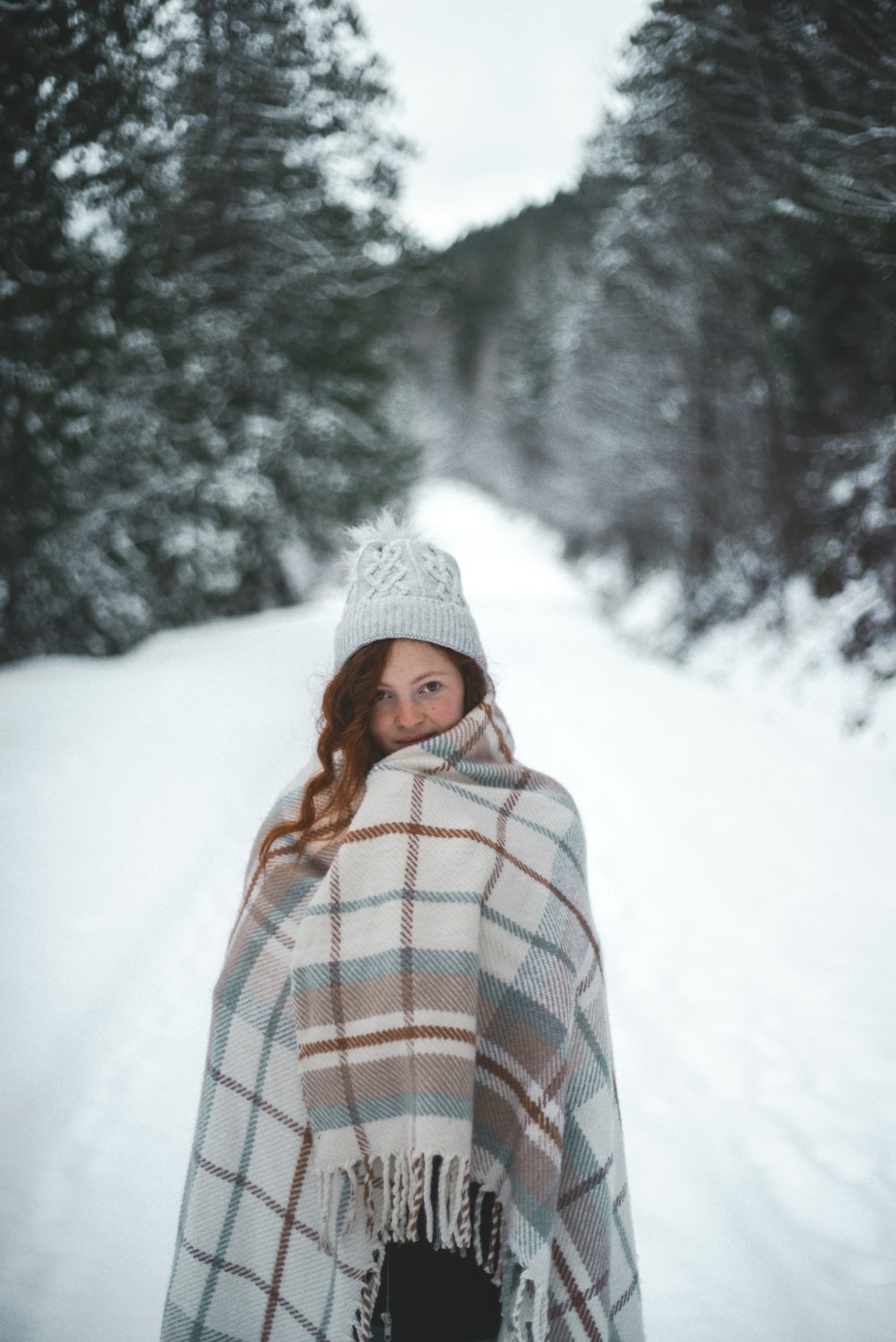 woman in white knit cap standing on snow covered ground during daytime