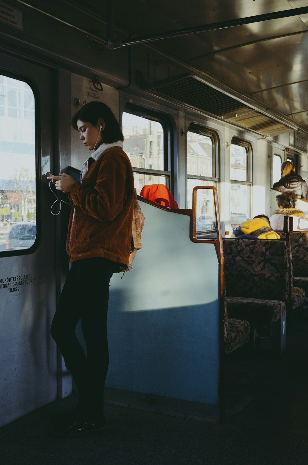 woman in orange hoodie standing in train