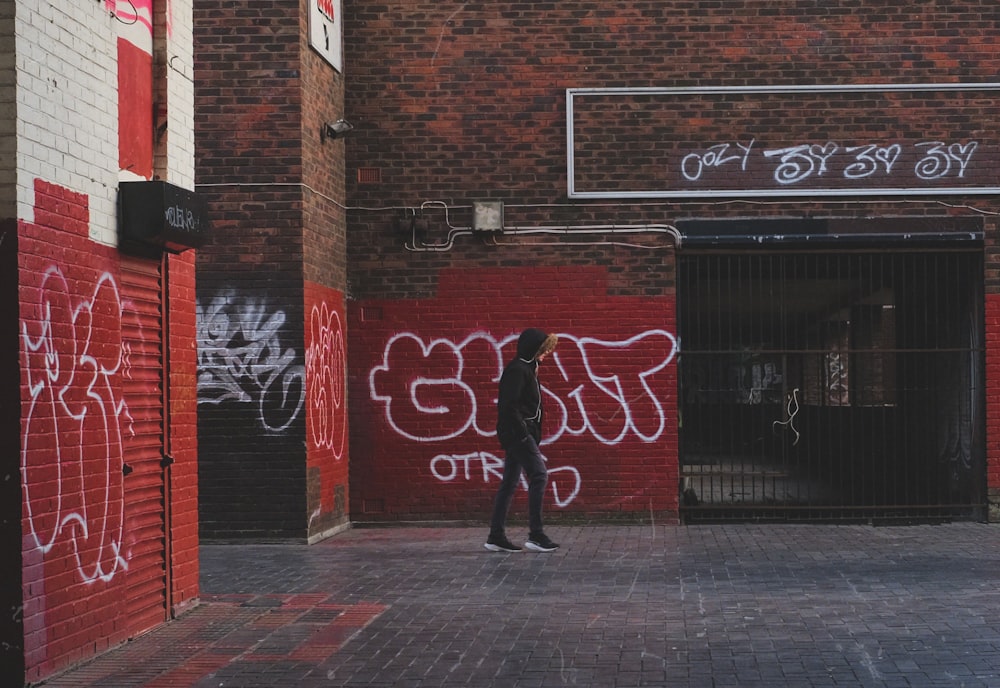 woman in black jacket walking on sidewalk during daytime