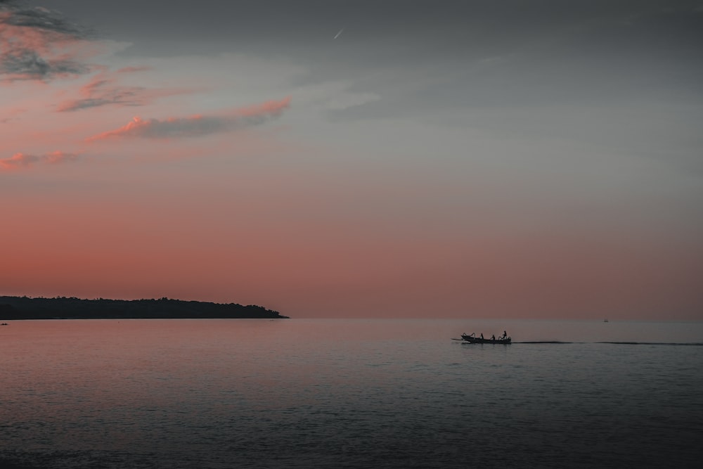 silhouette of boat on sea during sunset