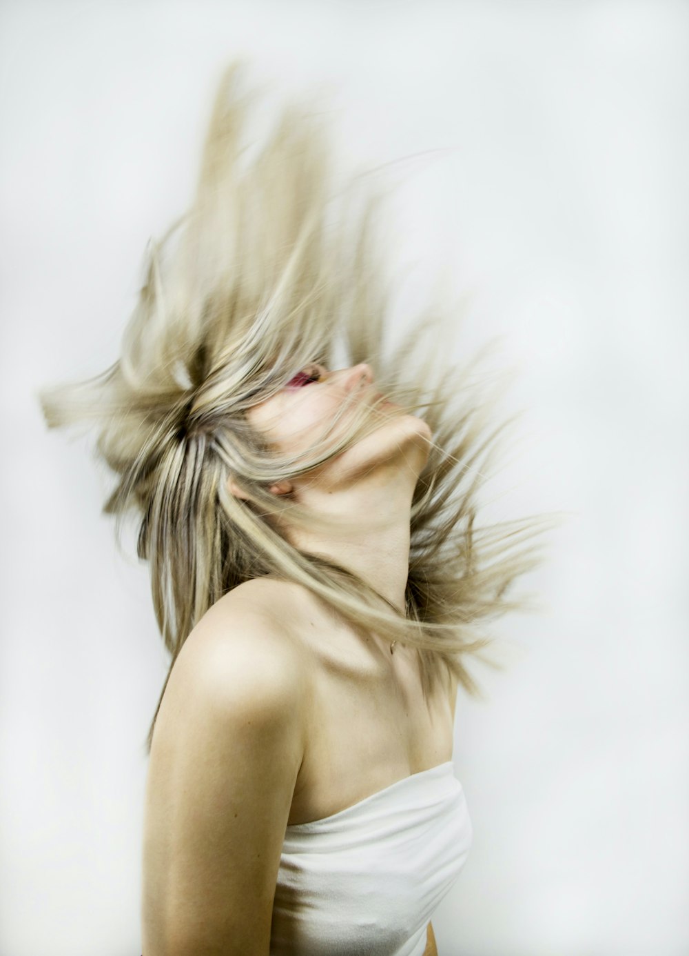 woman in white spaghetti strap top covering her face