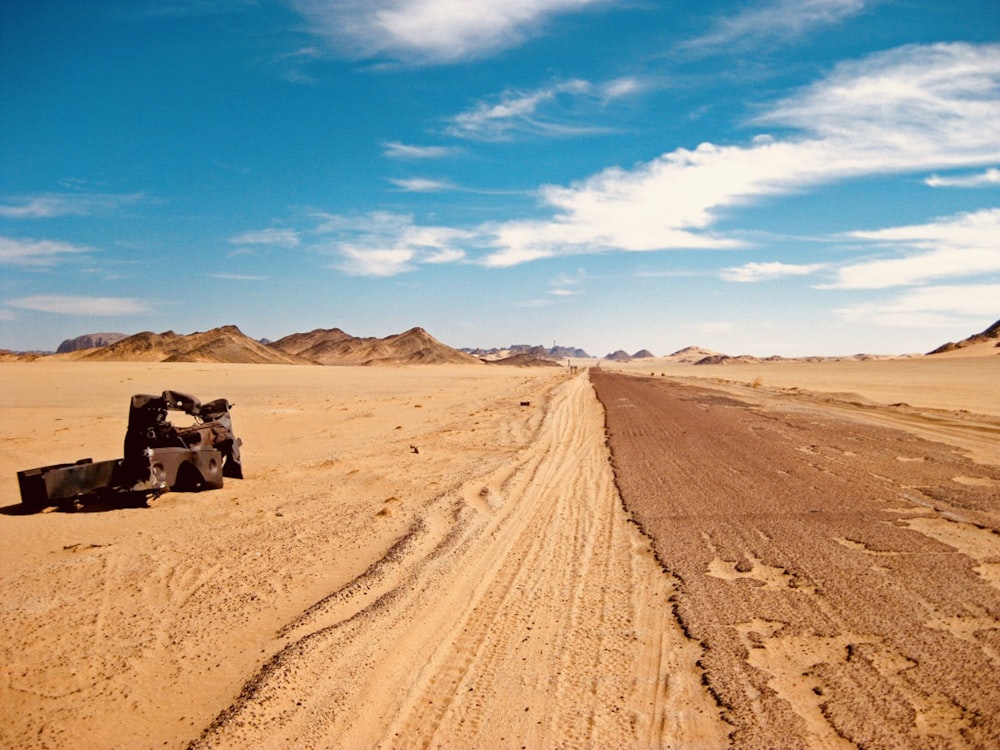 Schwarzer SUV tagsüber auf braunem Sand unter blauem Himmel