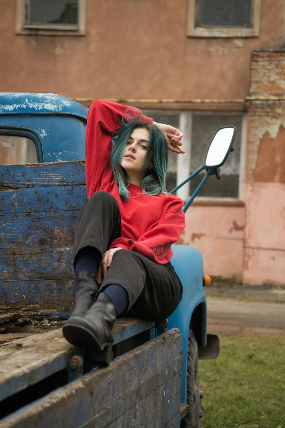 woman in red long sleeve shirt and black pants sitting on blue and red car