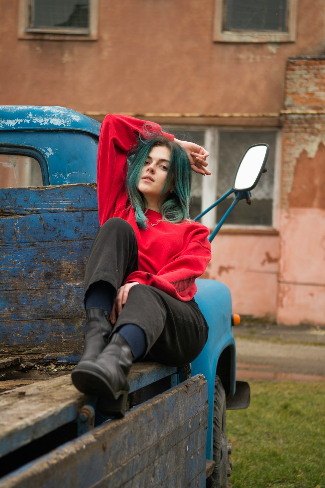 woman in red long sleeve shirt and black pants sitting on blue and red car