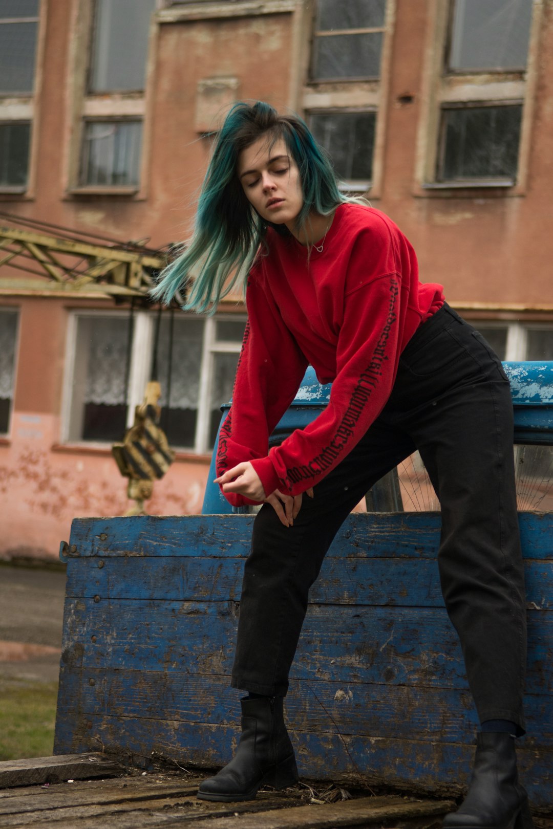 woman in red long sleeve shirt and blue denim jeans standing on blue wooden bench during