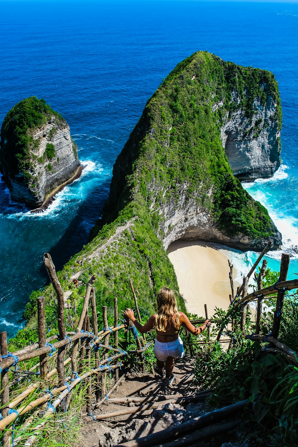 woman in black tank top and blue denim shorts climbing on brown rock formation during daytime