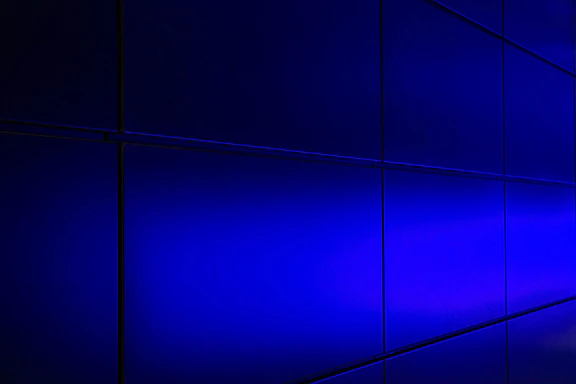 A sleek brushed aluminum panel with glowing electric indigo pixel art fading into vivid cyan accents.