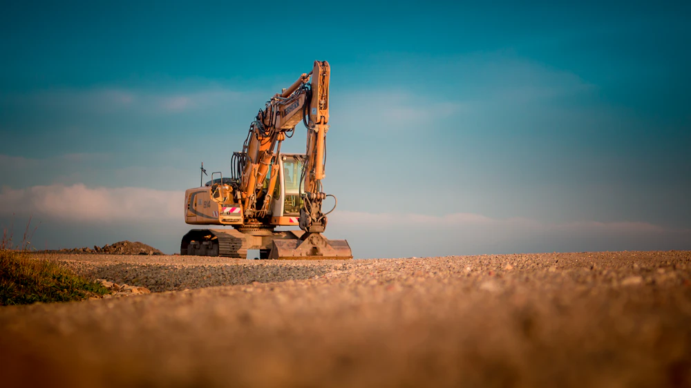 Yellow and black excavator digging on a sandy job site