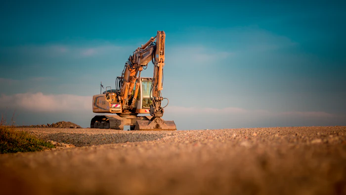 Yellow and black excavator digging on a sandy job site