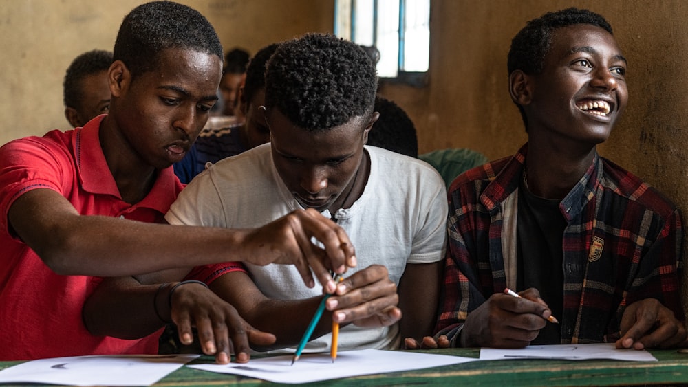 homme en chemise à col rond gris tenant un stylo