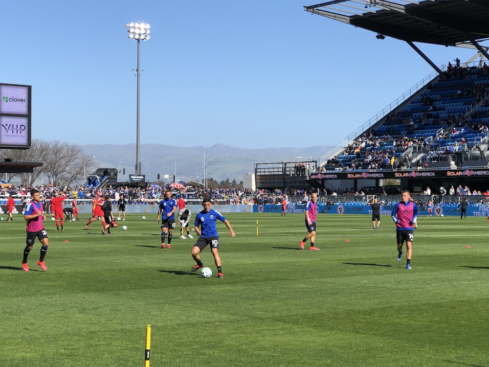 Personas jugando al fútbol en un campo de césped verde durante el día