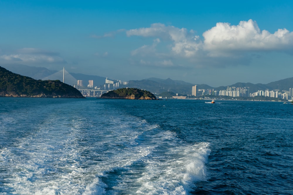 body of water near city buildings under blue and white sunny cloudy sky during daytime