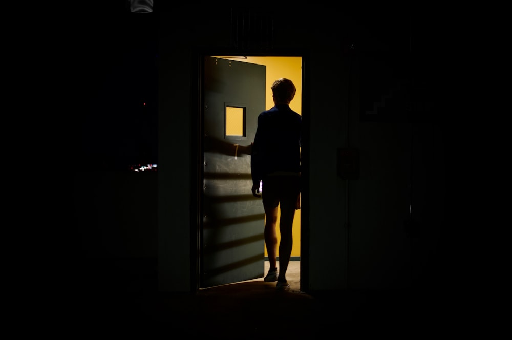 白い木製のドアの前に立つ黒いジャケットの男