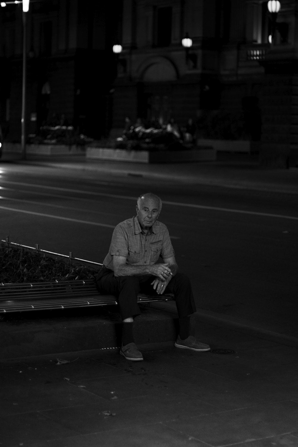 grayscale photo of man sitting on bench