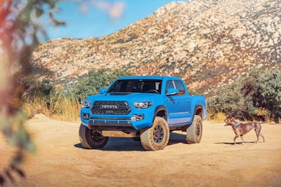 blue suv on brown dirt road during daytime toyota teams background