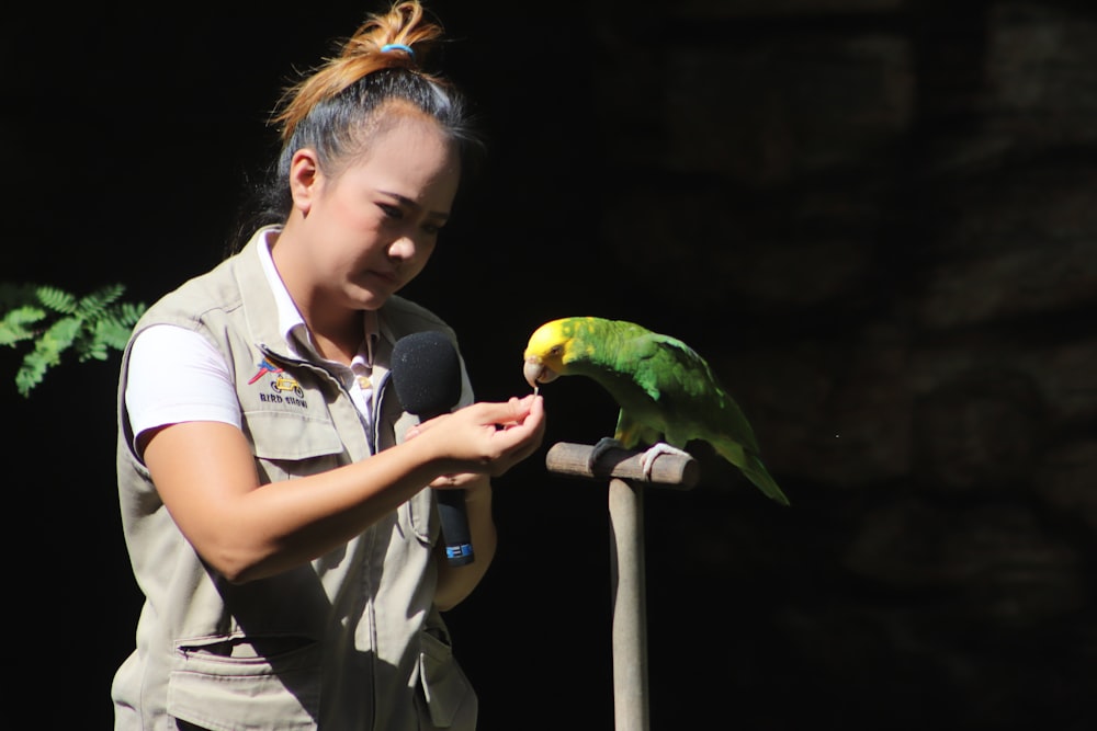 boy in white polo shirt holding green and yellow bird
