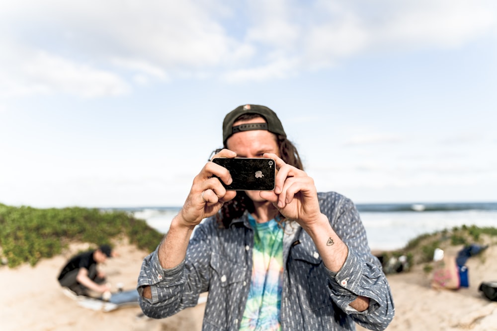 man in blue and white long sleeve shirt holding black smartphone