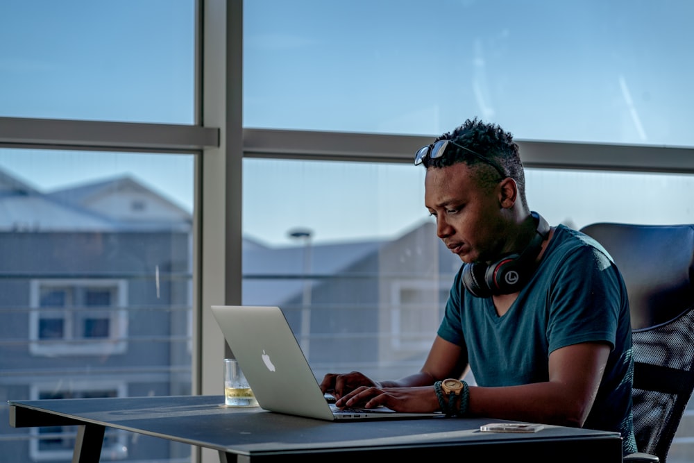 man in blue and red polo shirt using macbook