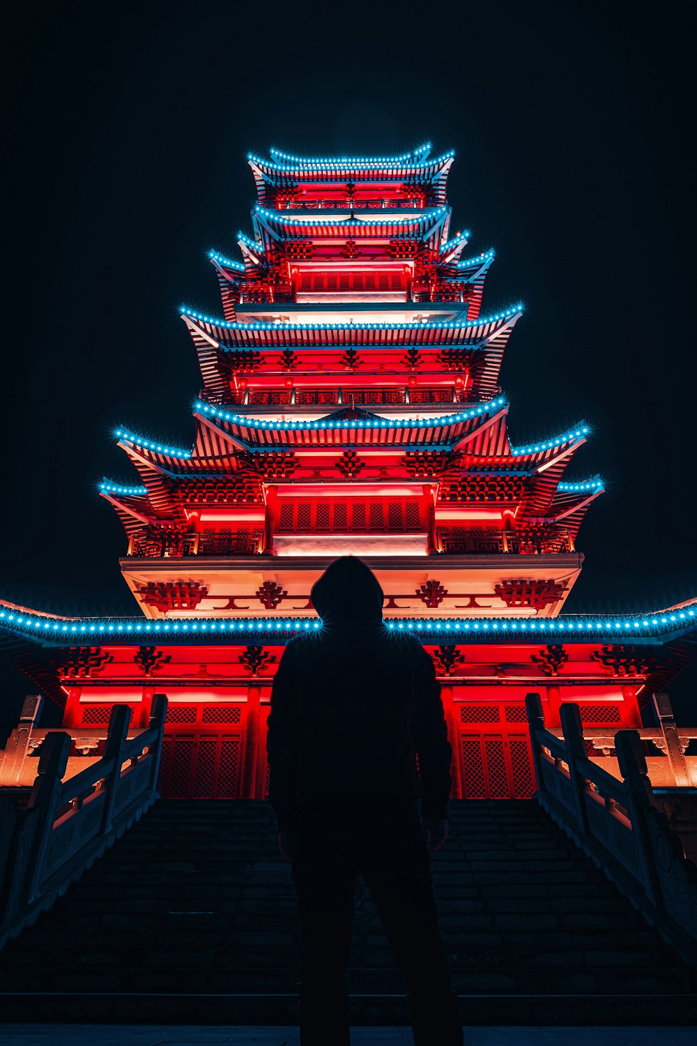 Femme en chemise noire à manches longues debout devant le temple pendant la nuit