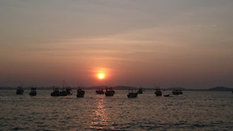 Sunset view from the shore of Santa Marta with silhouettes of boats and calm sea.