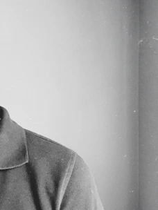 Monochrome image of a sharply tailored shirt collar casting a shadow on a dark background.