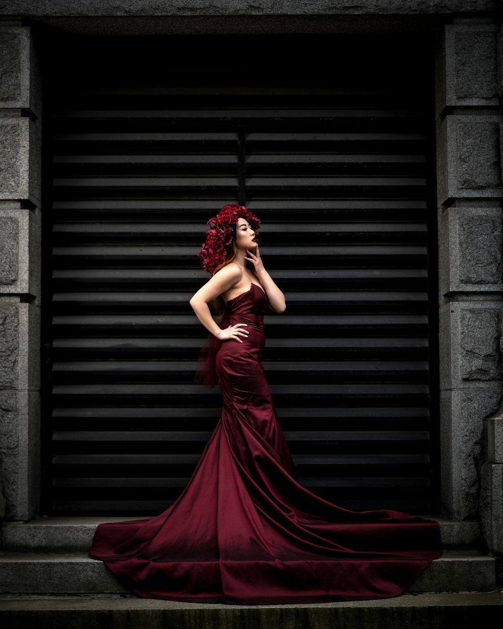 Femme en robe rouge debout près d’un mur de briques brunes