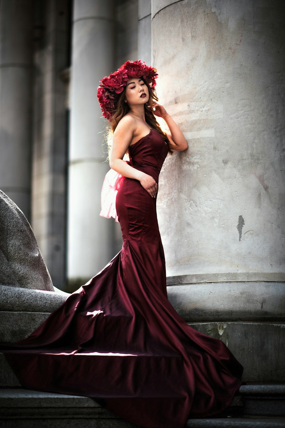 woman in red tube dress leaning on gray concrete wall